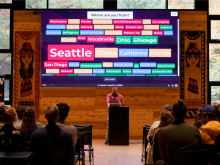 Projector showing answers to where are you from with different cities and states, with Chris Schaeffer at the podium in front.