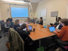 People sitting at a table looking at a presentation screen