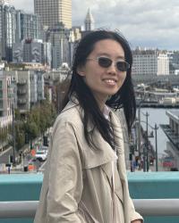 image of a woman with dark hair wearing dark sunglasses in front of a city background
