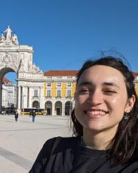 image of a woman smiling with long dark hair. there is a white marble building behind her.