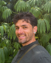 Zach Wellstood headshot in front of large green leaves.