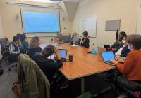 People sitting at a table looking at a presentation screen