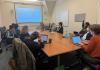 People sitting at a table looking at a presentation screen