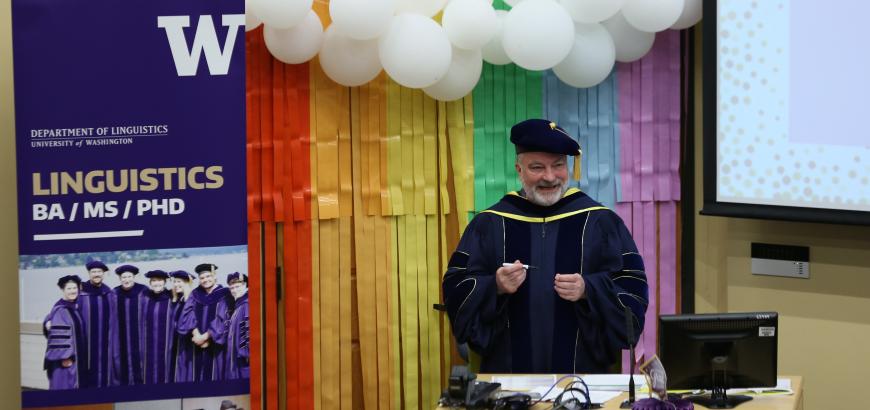Richard Wright speaking at graduation next to the Linguistics banner.