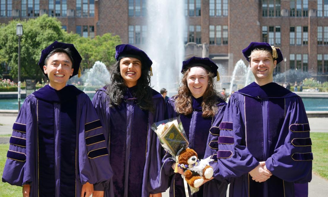 Four graduating students standing in front of the UW fountain